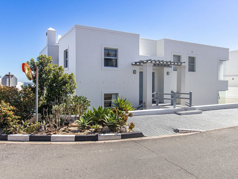 Modern white exterior facade featuring a paved driveway, pergola entrance, and clean architectural lines.