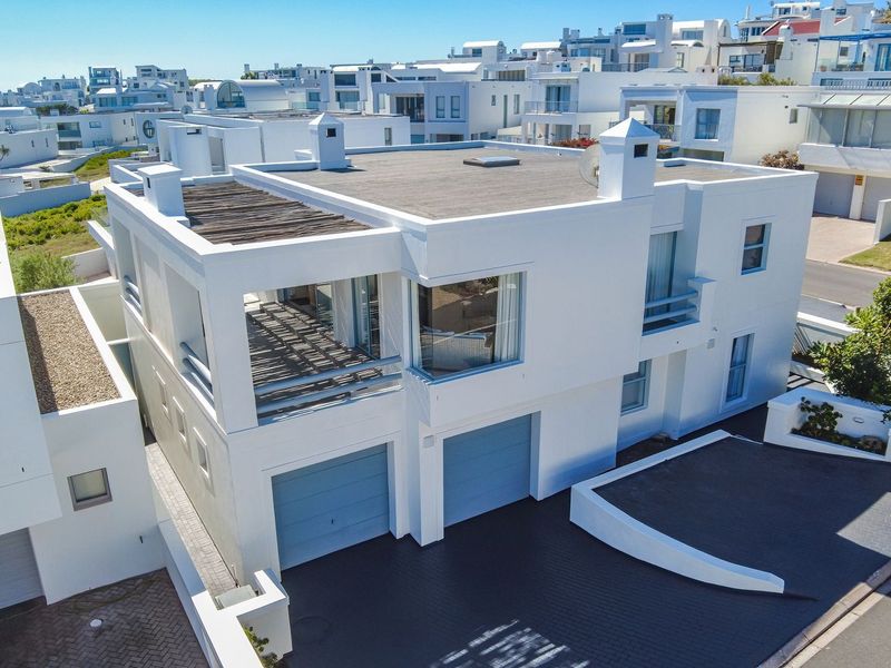 Aerial view of a modern two-story residential property featuring a double garage, flat roof design, and an upper-level balcony with a pergola.