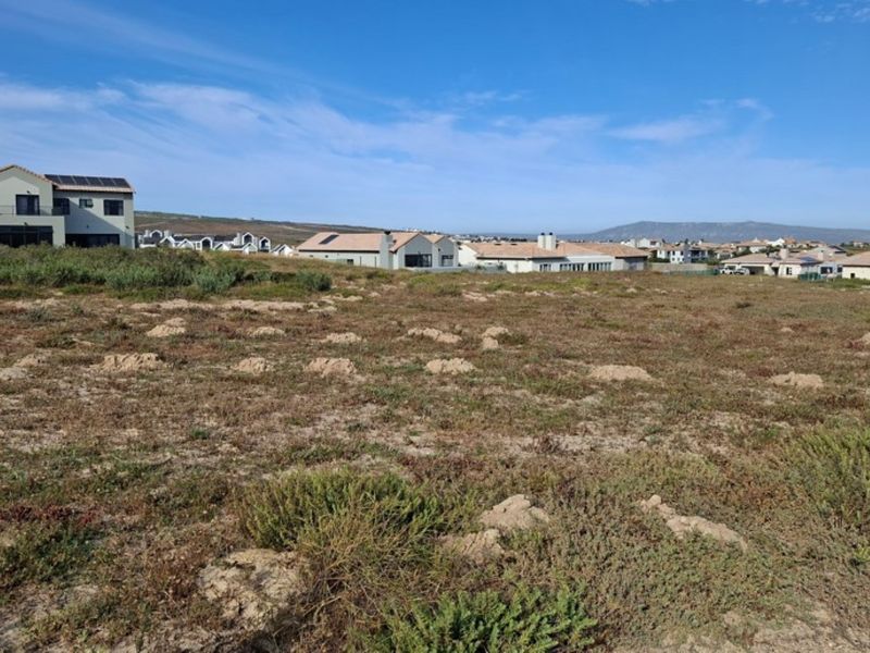 A view of a vacant residential plot of land in a developed estate, featuring natural vegetation and surrounding residential properties.