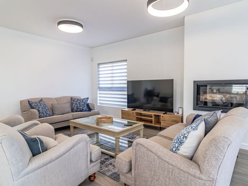 A modern, well-maintained living room featuring a built-in fireplace, recessed shelving, and contemporary flush mount lighting with neutral finishes.