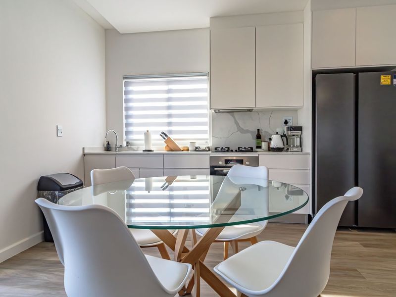 Modern open-plan kitchen featuring sleek cabinetry, stone countertops, integrated appliances, and durable laminate flooring, seamlessly connected to the dining area.
