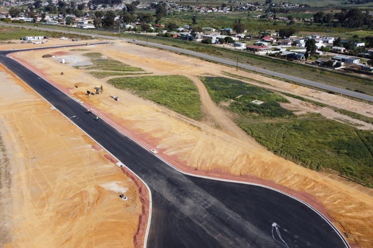 Aerial view of a developing industrial site featuring newly paved asphalt roads, concrete curbing, and cleared land ready for construction.