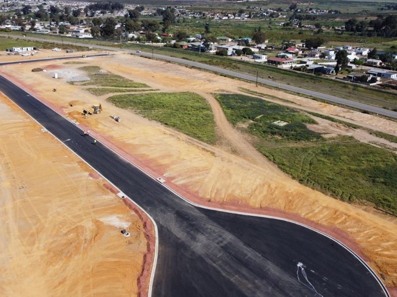 Aerial view of a developing industrial site featuring newly paved asphalt roads, concrete curbing, and cleared land ready for construction.
