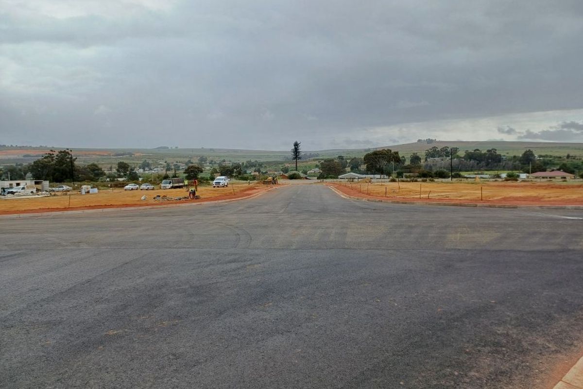 A view of a newly paved asphalt road within an industrial development site, featuring cleared land and surrounding landscape.
