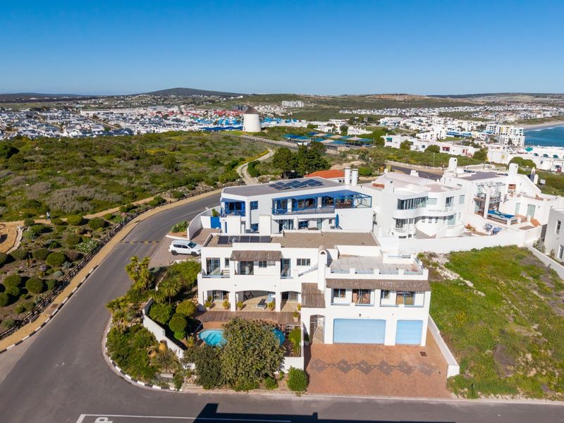 Aerial view of a coastal property featuring a swimming pool, double garage, solar panels, and multiple balconies in a residential estate setting.