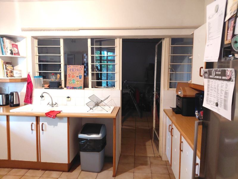 A functional kitchen featuring laminate countertops, double basin sink, and built-in cabinetry, with direct access to an adjacent utility or outdoor area.