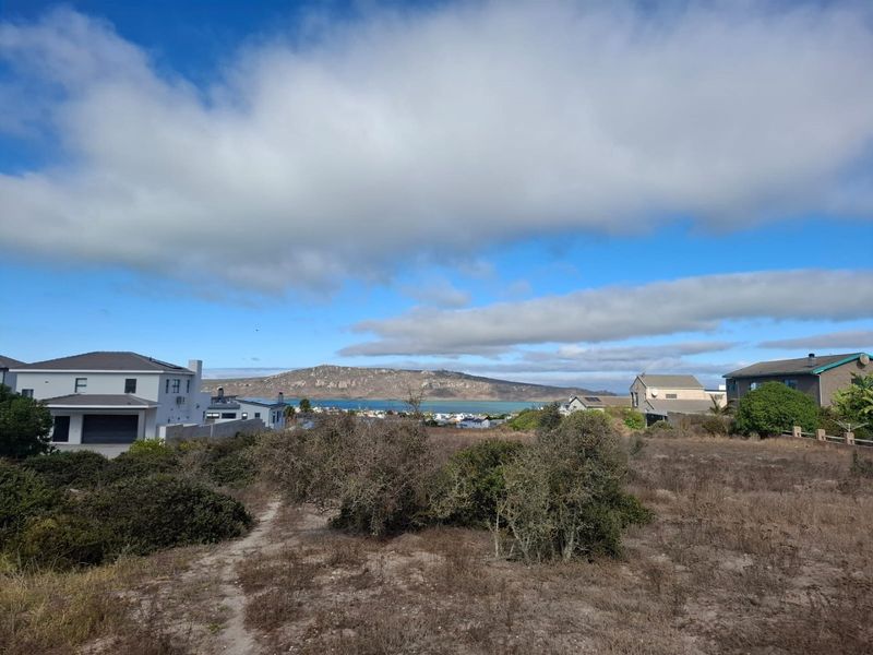 A scenic view overlooking the coastal landscape, surrounding residential properties, and distant mountains from the vacant residential land.