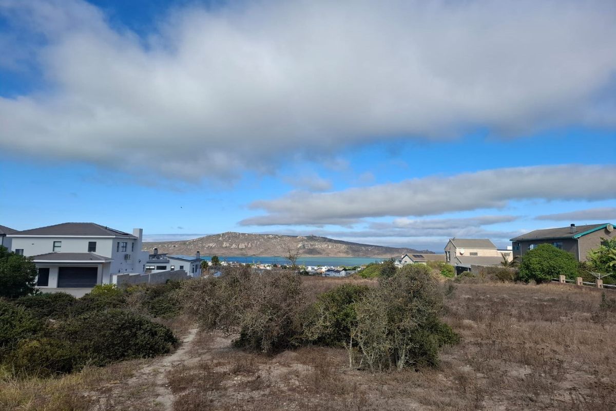 A scenic view overlooking the coastal landscape, surrounding residential properties, and distant mountains from the vacant residential land.