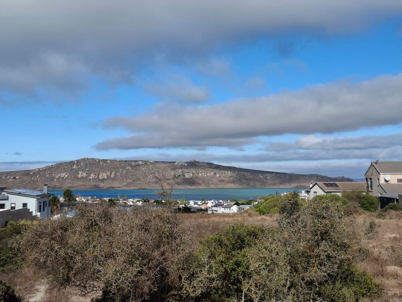 A scenic elevated view overlooking the coastal landscape, lagoon, and surrounding mountain range from the vacant residential property.