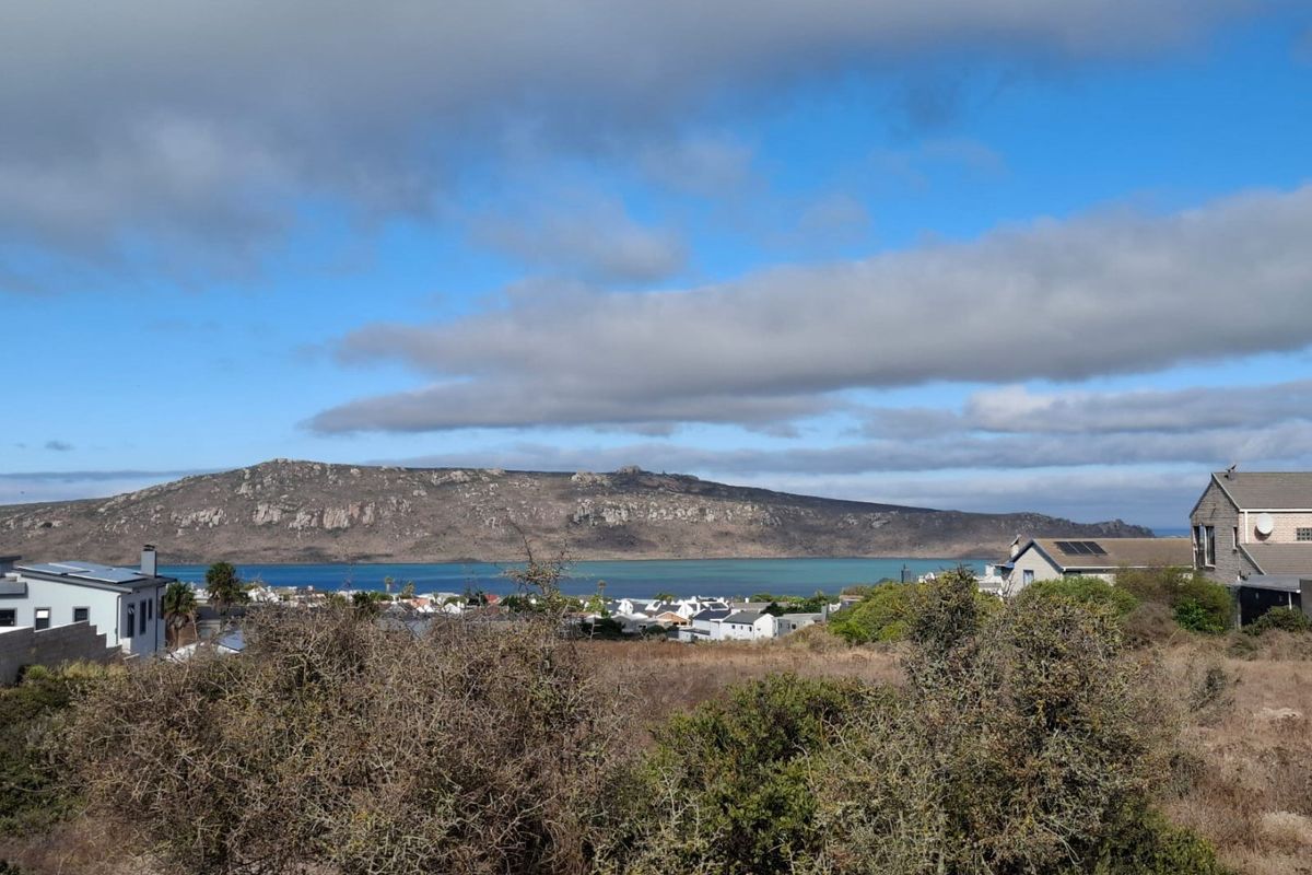 A scenic elevated view overlooking the coastal landscape, lagoon, and surrounding mountain range from the vacant residential property.