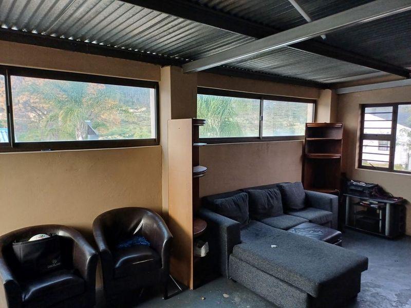 A living area featuring exposed steel beams, a corrugated metal ceiling, and large sliding windows providing natural light and views.