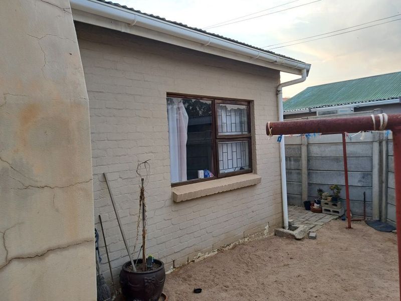 Rear exterior view of the property showing brick walling with visible structural cracking and standard window security features.