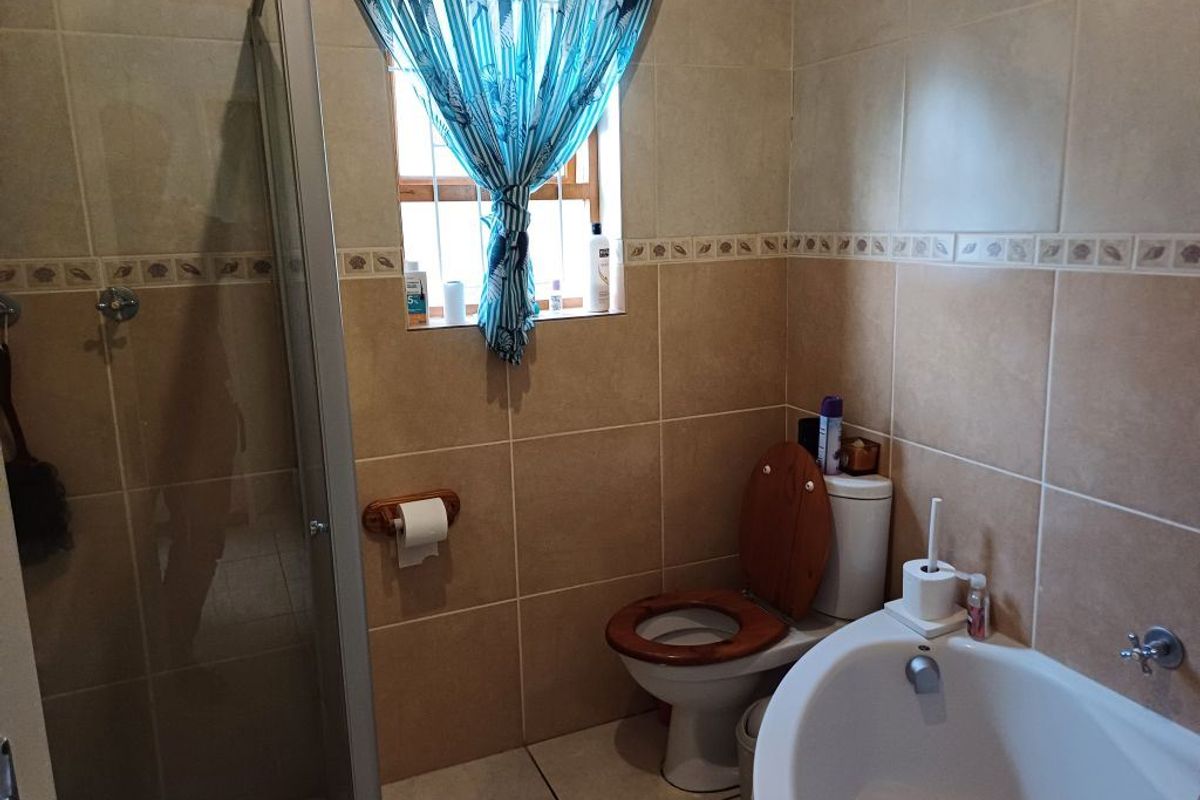 A functional bathroom featuring a shower enclosure, toilet, and neutral ceramic wall and floor tiling.