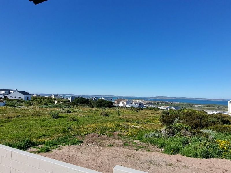 A wide-angle view overlooking a coastal landscape with surrounding residential properties and distant water views.