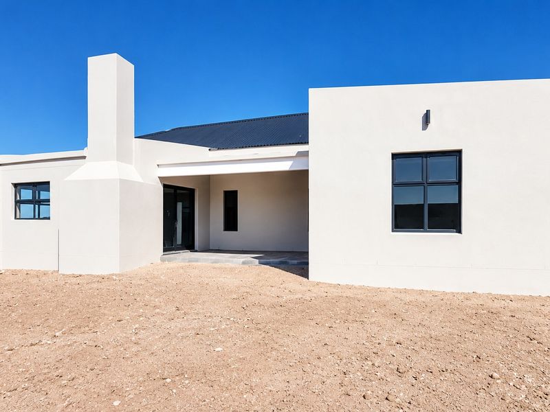 Modern single-story residence featuring a clean white facade, a prominent chimney, a covered patio area, and dark metal roofing.