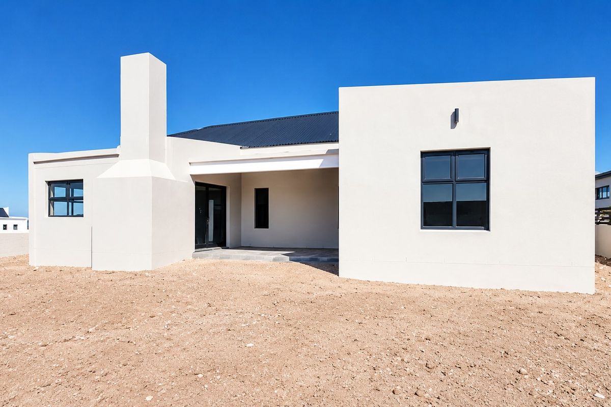 Modern single-story residence featuring a clean white facade, a prominent chimney, a covered patio area, and dark metal roofing.