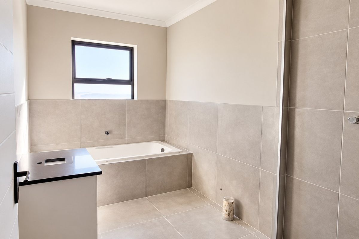 Modern bathroom featuring a built-in bathtub, neutral wall tiles, and a vanity cabinet with a stone countertop.