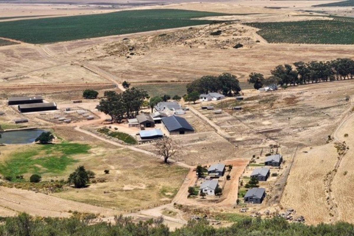 An aerial view of a large farm property featuring multiple outbuildings, a dam, and extensive agricultural land.