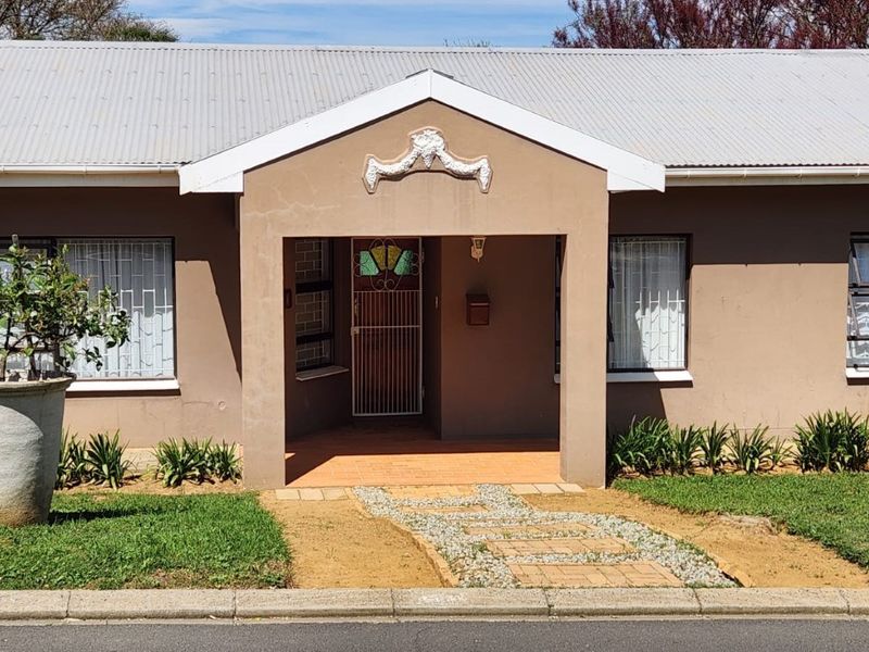 Front elevation of a single-story house featuring a covered entrance porch, corrugated metal roof, and security-fitted windows.