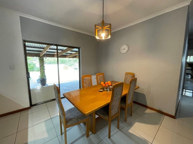 A dining room featuring tiled flooring, a pendant light fixture, and a sliding glass door providing access to an outdoor patio area.
