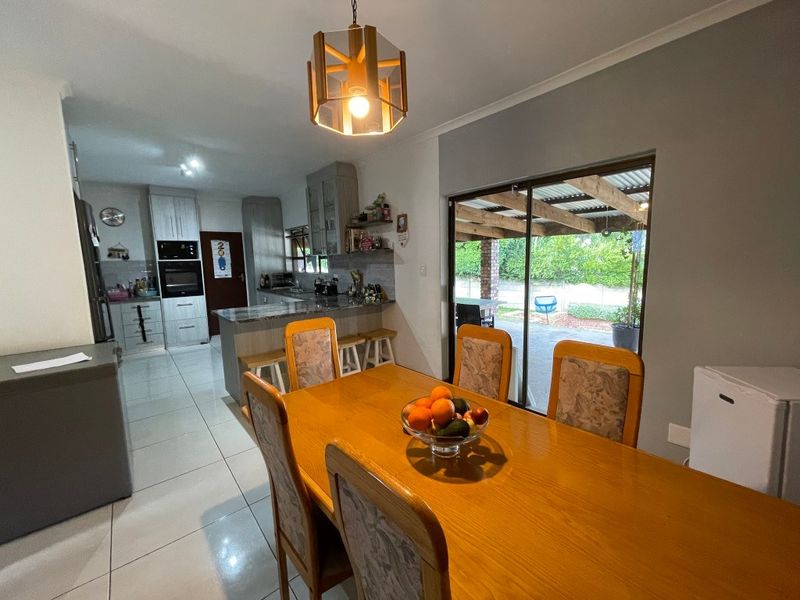 Open-plan kitchen and dining area featuring tiled floors, granite countertops, built-in cabinetry, and direct access to a covered outdoor patio.