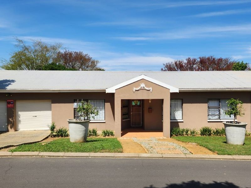 Front elevation of a single-story house featuring a metal roof, integrated garage, and a paved entrance path with security features.