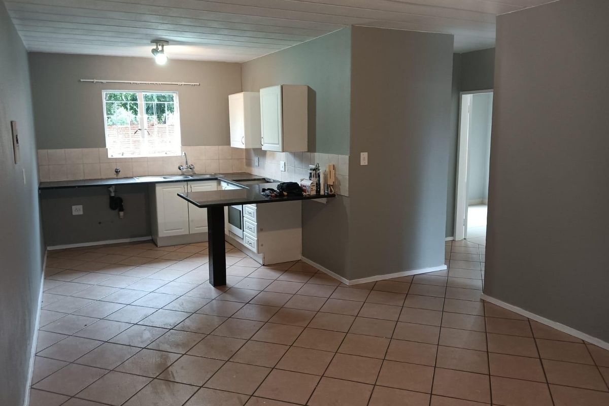 Open-plan kitchen featuring built-in cabinetry, a breakfast bar, tiled backsplash, and ceramic flooring, offering a functional layout ready for personalization.