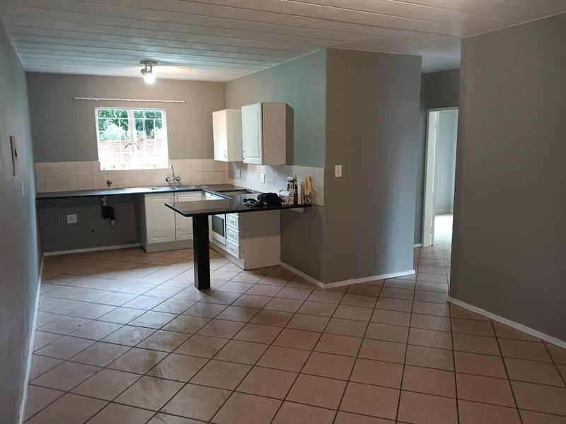 Open-plan kitchen featuring built-in cabinetry, a breakfast bar, tiled backsplash, and ceramic flooring, offering a functional layout ready for personalization.