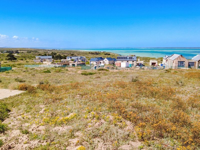 An aerial view of a coastal residential development site featuring multiple houses under construction with scenic ocean views.