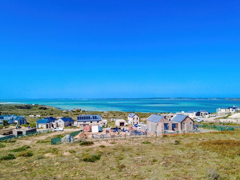 Aerial view of a coastal residential development under construction, showcasing the surrounding landscape and proximity to the ocean.
