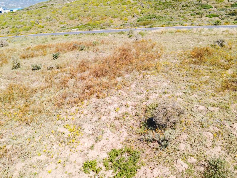An aerial view of a vacant residential plot featuring natural coastal vegetation and surrounding landscape.