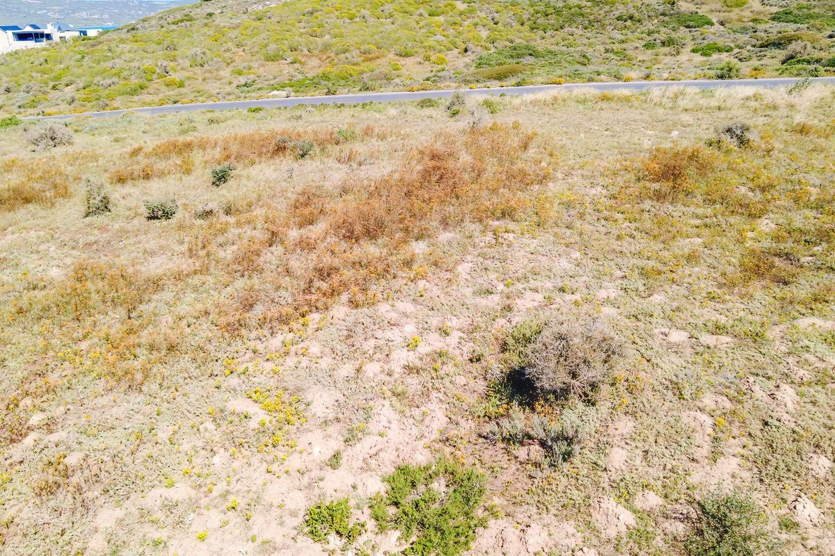 An aerial view of a vacant residential plot featuring natural coastal vegetation and surrounding landscape.