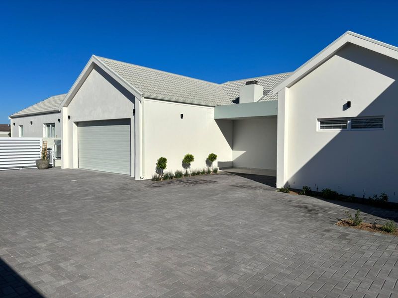 Modern front elevation featuring a paved driveway, tiled roof, and integrated garage, showcasing a clean and well-maintained exterior facade.