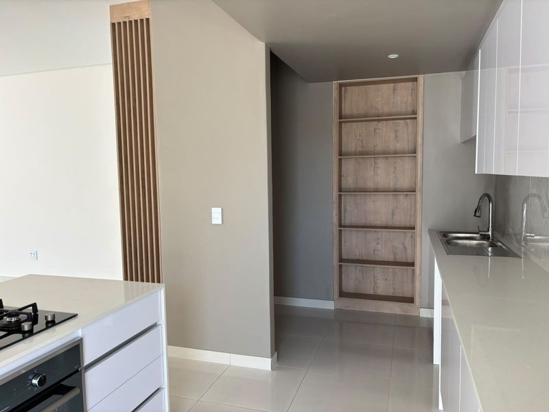 Modern kitchen featuring sleek white cabinetry, quartz countertops, integrated gas hob and oven, and a stylish timber-slatted feature wall with built-in shelving.