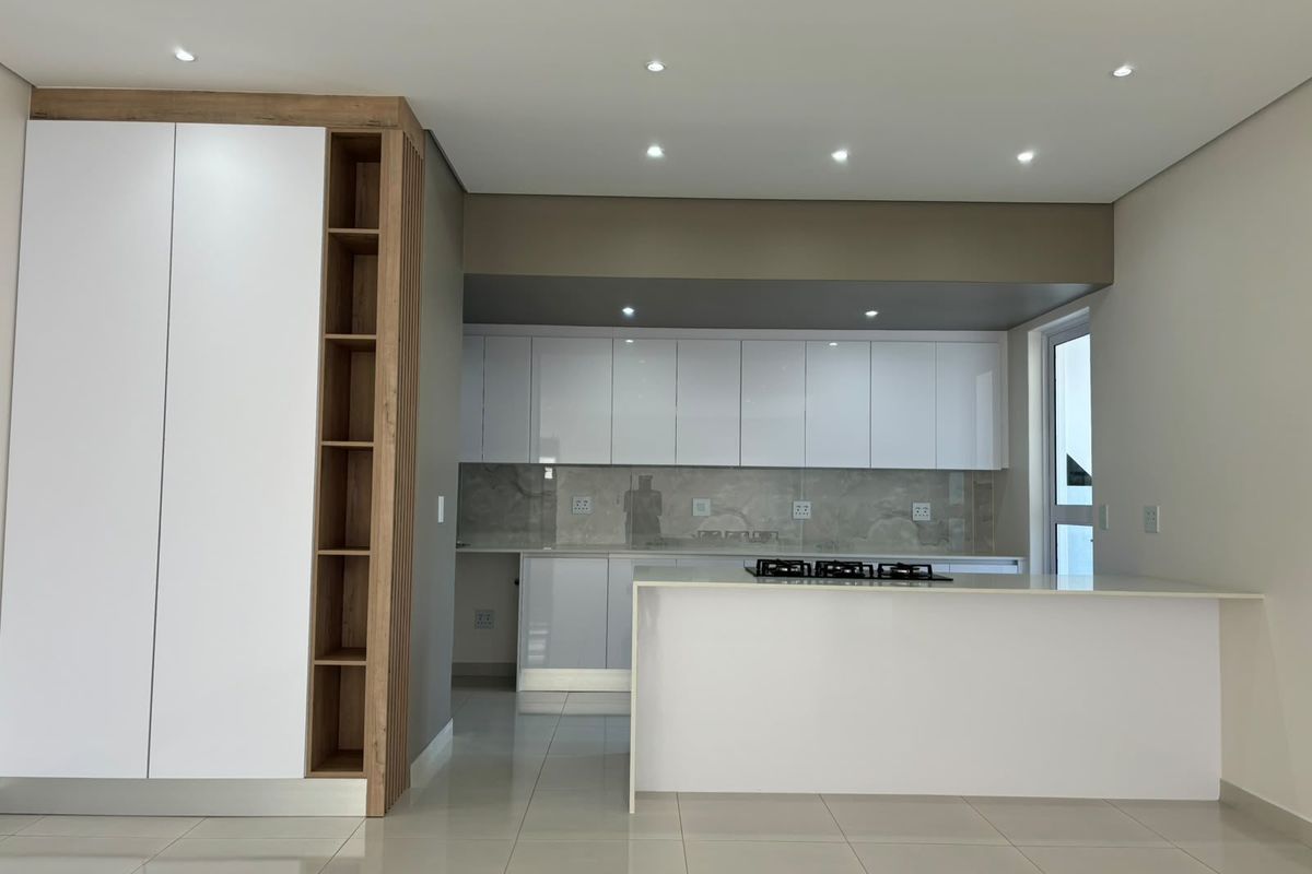 Modern kitchen featuring sleek white cabinetry, stone countertops, a built-in gas hob, and high-quality tiled flooring in a clean, minimalist design.