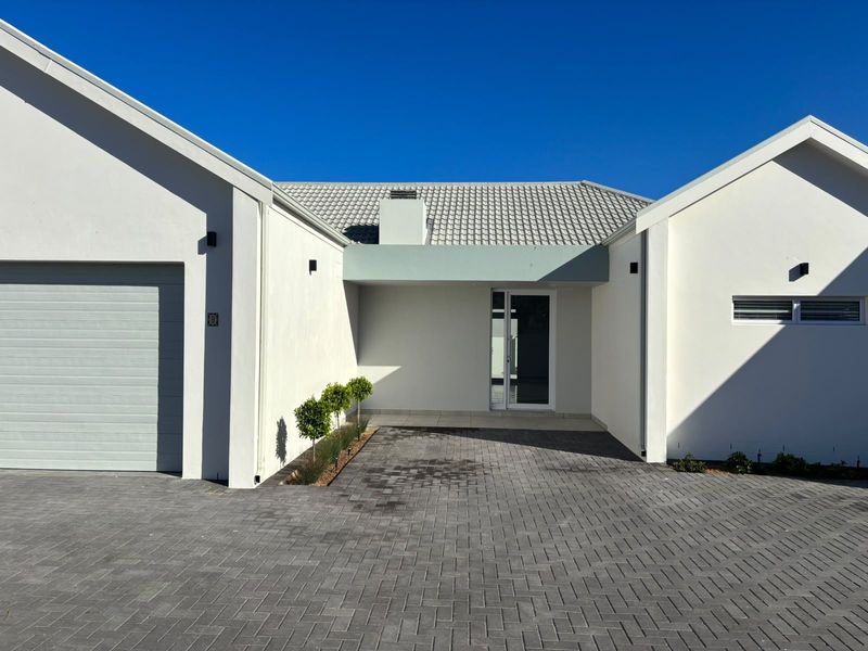 A modern front elevation featuring a paved driveway, a single garage, and a clean, minimalist entrance with a tiled roof.