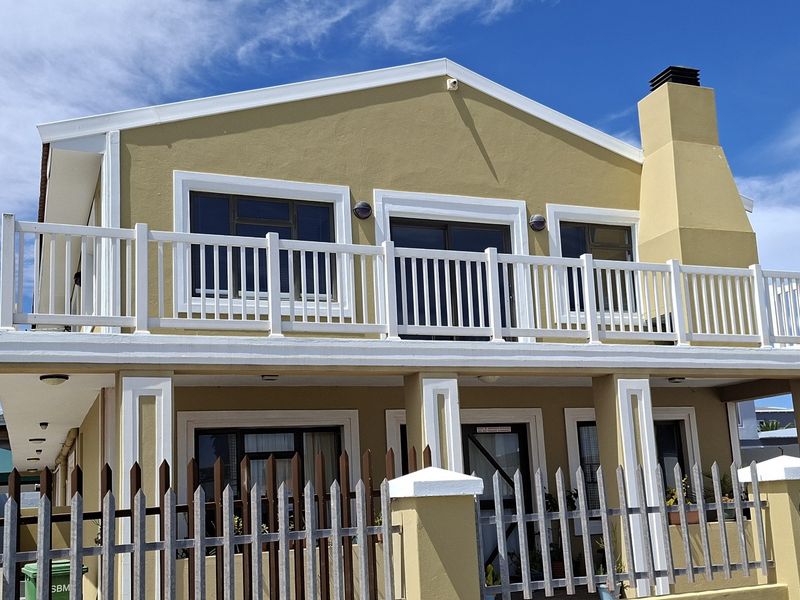 Front elevation of a two-story apartment building featuring a balcony, chimney, and secure perimeter fencing.