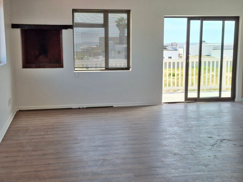 Spacious living area featuring a built-in fireplace, laminate flooring, and sliding glass doors leading to an outdoor balcony.