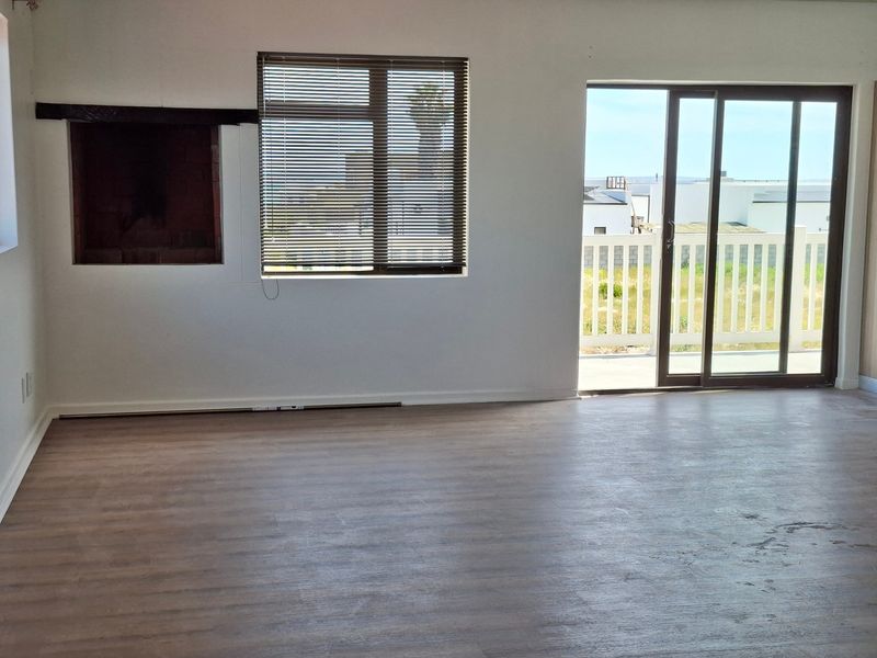 An empty living room featuring laminate flooring, a built-in fireplace, and sliding glass doors providing access to an outdoor balcony area.