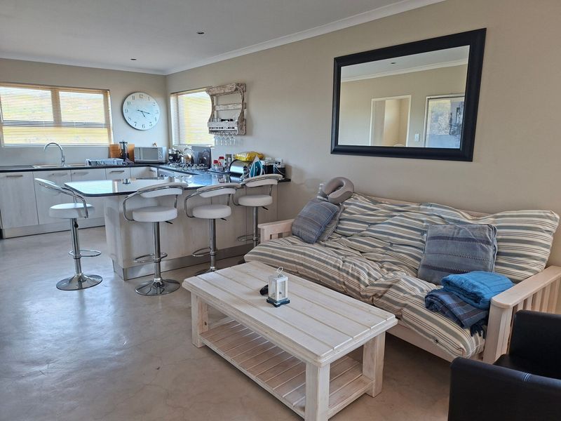 Spacious open-plan living area featuring a modern kitchen with a granite-topped island, polished concrete floors, and neutral wall finishes.