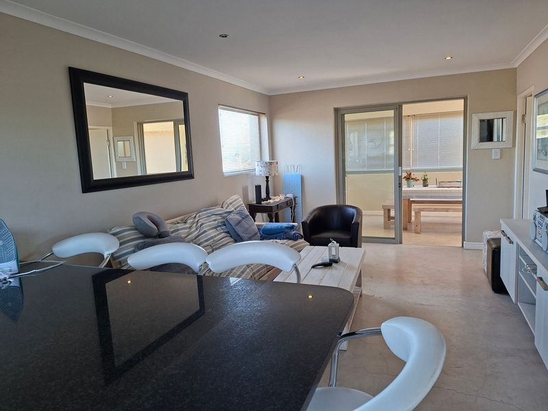 Open plan living area featuring polished concrete floors, recessed lighting, and a sliding glass door leading to an outdoor patio space.