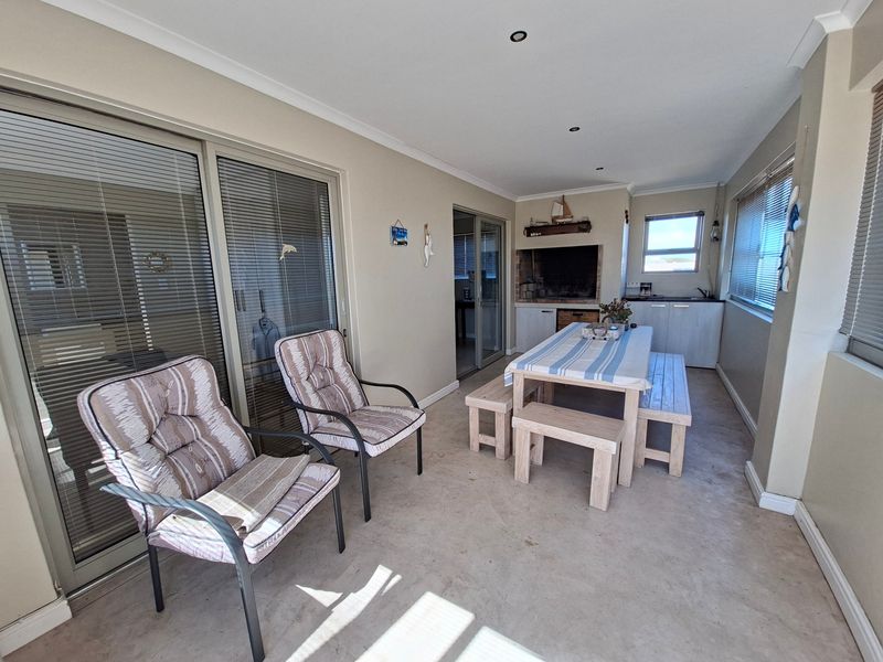 Enclosed patio featuring a built-in braai, kitchenette area with sink, and sliding glass doors providing access to the main living space.