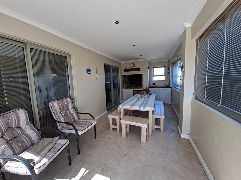 Covered patio area featuring a built-in braai, recessed lighting, and sliding glass doors, providing a functional space for outdoor dining and entertainment.