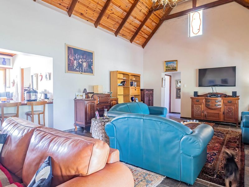 Spacious open-plan living area featuring a high vaulted timber ceiling with exposed beams, tiled flooring, and an integrated kitchen breakfast bar.
