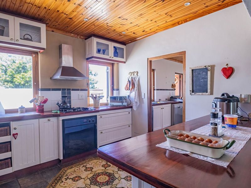 A rustic-style kitchen featuring timber ceilings, white cabinetry, timber countertops, and a built-in oven with gas hob, offering a warm and functional cooking space.