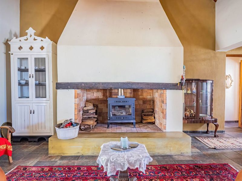 Spacious living room featuring a prominent masonry fireplace with a built-in wood-burning stove, timber mantelpiece, and durable tiled flooring.