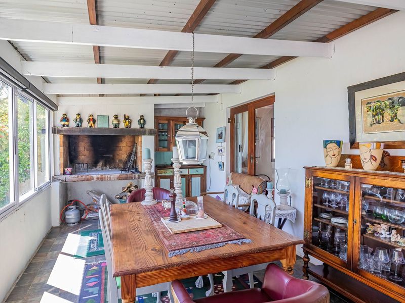Enclosed patio area featuring a built-in braai, exposed beam ceiling, and slate tile flooring, offering a functional space for indoor-outdoor dining.