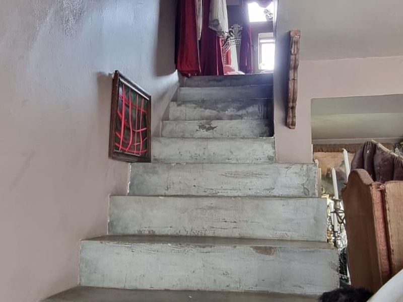 A staircase featuring raw concrete steps leading to an upper level, requiring cosmetic updates to improve the overall finish and aesthetic appeal.
