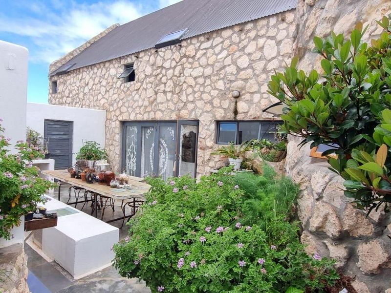 A charming rear courtyard featuring rustic stone wall cladding, a metal roof with skylights, and a built-in bench area with access via glass sliding doors.