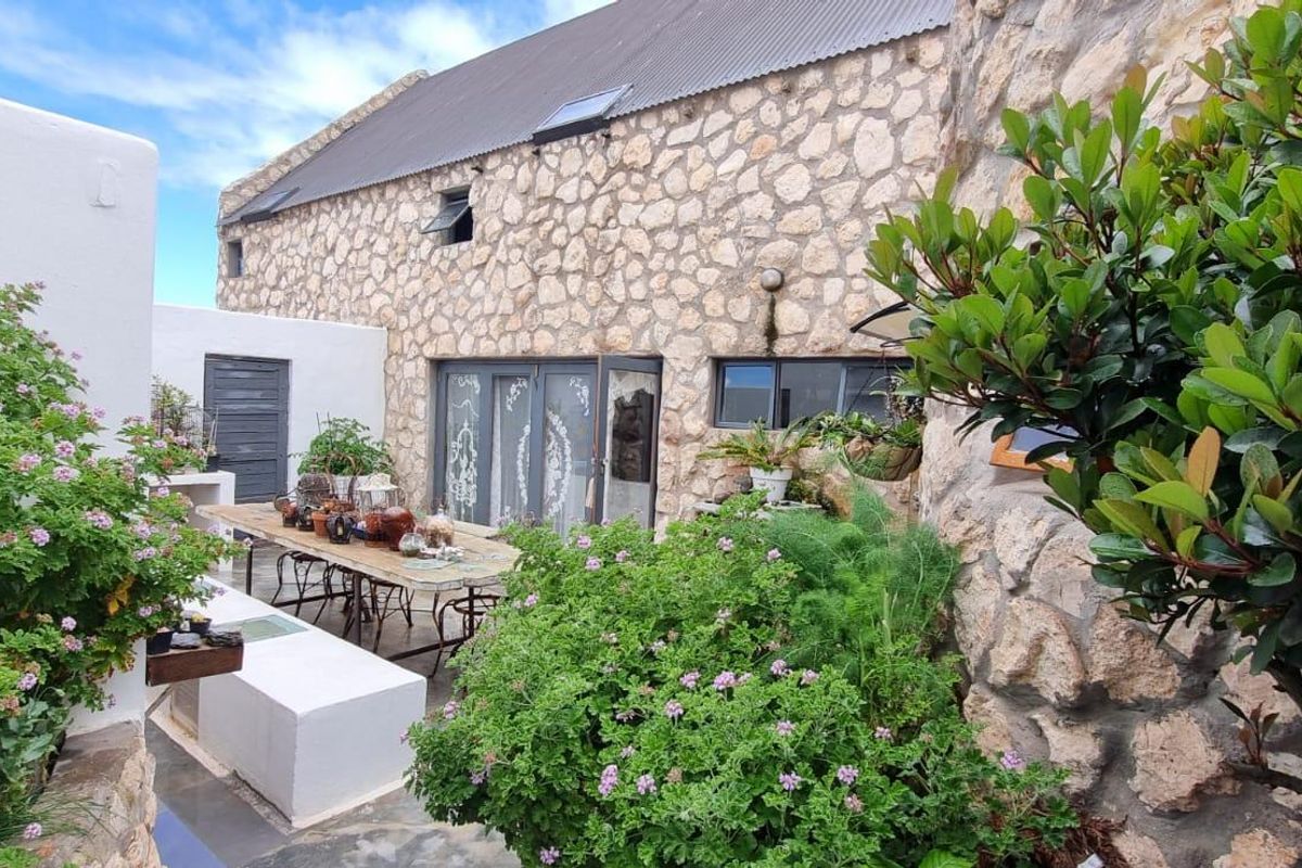 A charming rear courtyard featuring rustic stone wall cladding, a metal roof with skylights, and a built-in bench area with access via glass sliding doors.